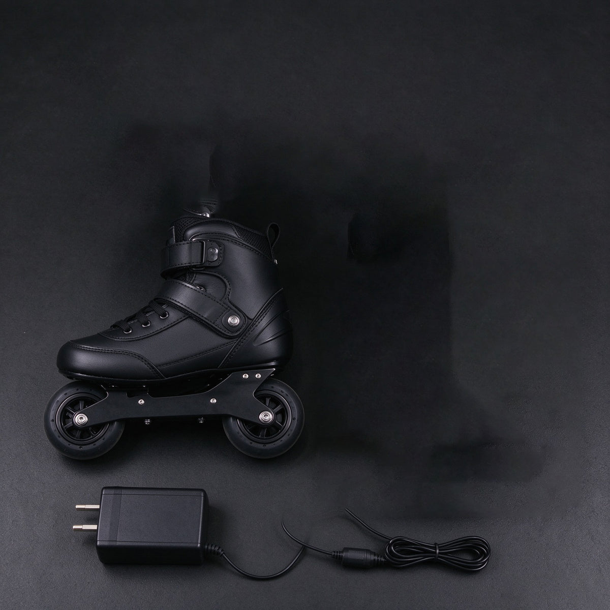 Pair of black electric skates with a charger